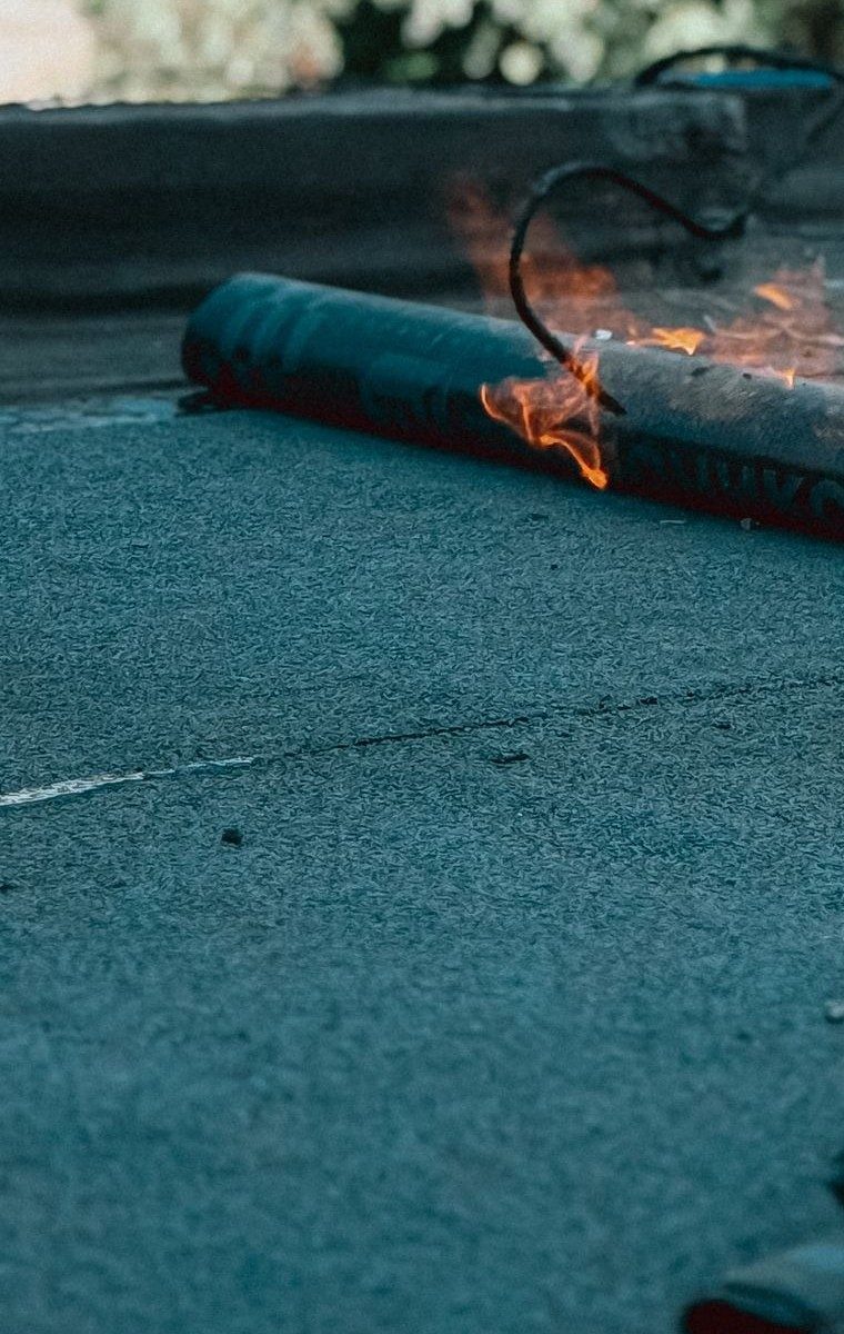 Torch-on felt membrane being flame-welded on a flat roof